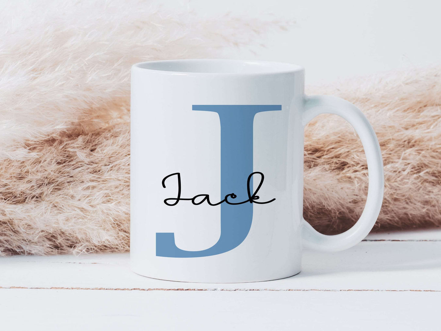 white mug with a large blue letter J printed on it with the name Jack printed in a black script font over the top