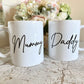 set of two white mugs. One has the text mummy printed on in a script font, the other has daddy printed on