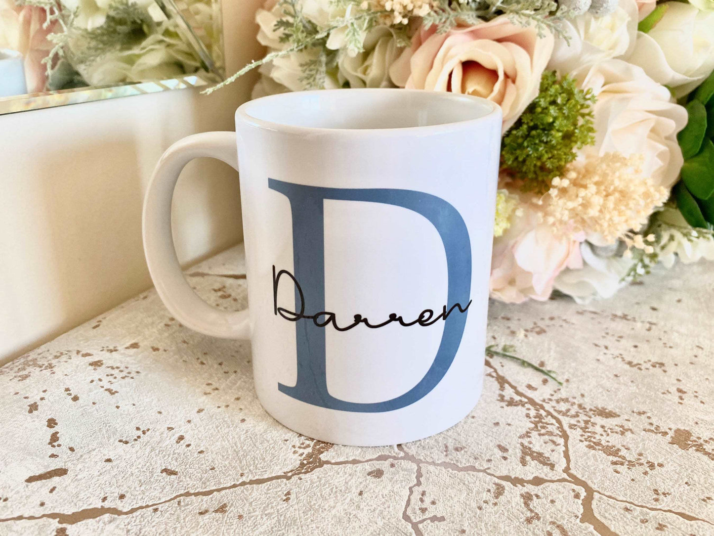 white mug with large blue letter printed with the name Darren printed over in a script font